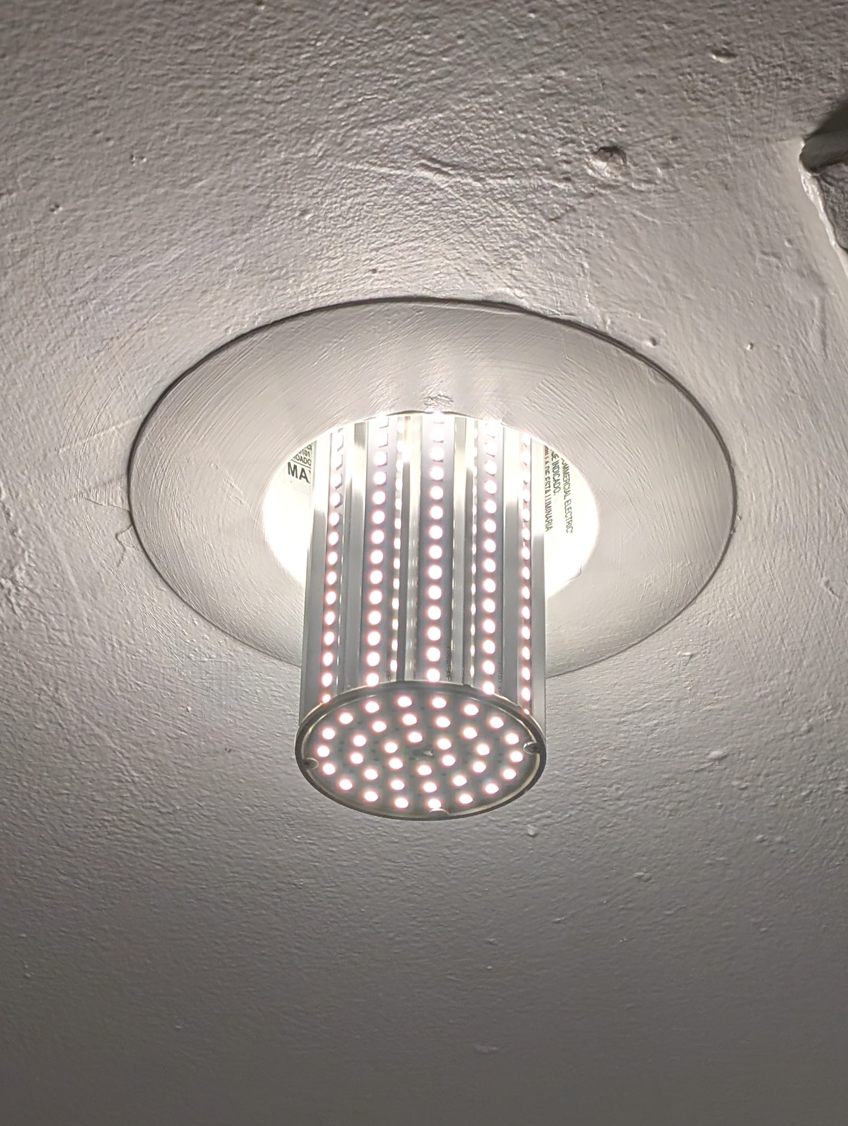 LED ceiling light fixture with a cylindrical design, emitting bright light, mounted in a recessed housing.